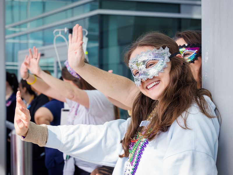 Child life affiliated student Sophie Patikas waves as the Mississippi Department of Public Safety Mardi Gras parade rolls by.