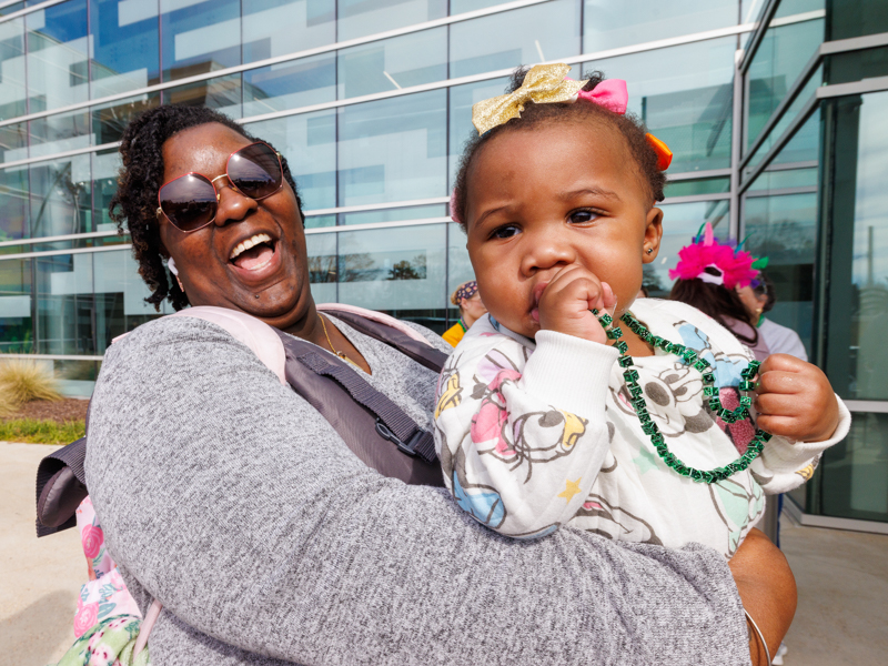 A Mississippi Highway Patrol officer Aaron Spann delivers Mardi Gras beads to Madelyn Bush, held by her mom, London Williams-Bush.