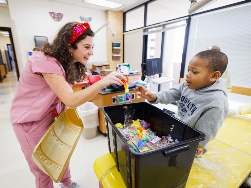 Pediatric dental resident, Dr. Anne Marie Hreish, helps Lamount Harper of Biloxi pick out toys from the treasure chest.