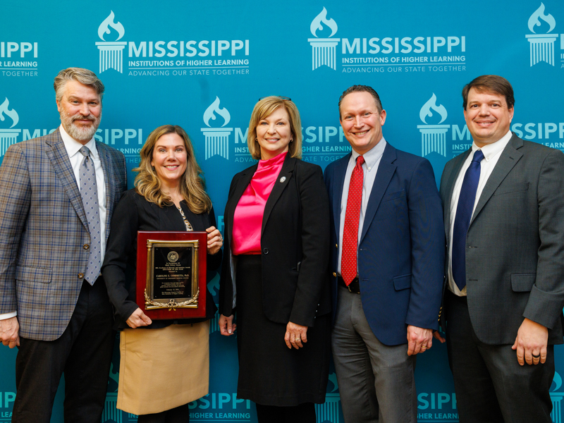 Congratulating Compretta, second from left, on her accomplishment are, from left, husband Jonathan Compretta; Dr. LouAnn Woodward, vice chancellor for health affairs; Dr. Joshua Mann, chair of preventive medicine; and Dr. Lee Bidwell, associate vice chancellor for research. Jay Ferchaud/ UMMC Photography 