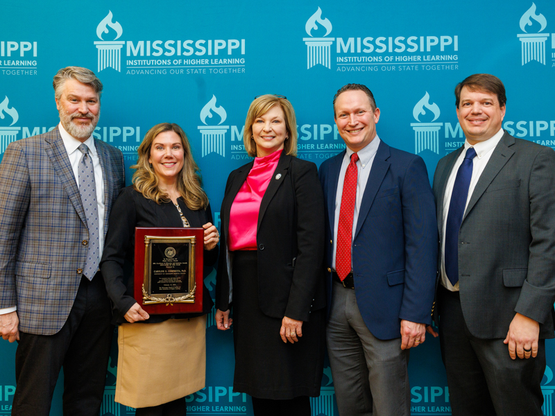 Congratulating Compretta, second from left, on her accomplishment are, from left, husband Jonathan Compretta; Dr. LouAnn Woodward, vice chancellor for health affairs; Dr. Joshua Mann, chair of preventive medicine; and Dr. Lee Bidwell, associate vice chancellor for research. Jay Ferchaud/ UMMC Photography