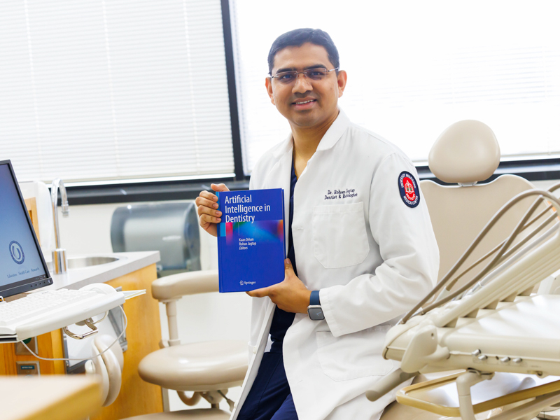 Dr. Rohan Jagtap holds his book, "Artificial Intelligence in Dentistry." Melanie Thortis/ UMMC Photography 