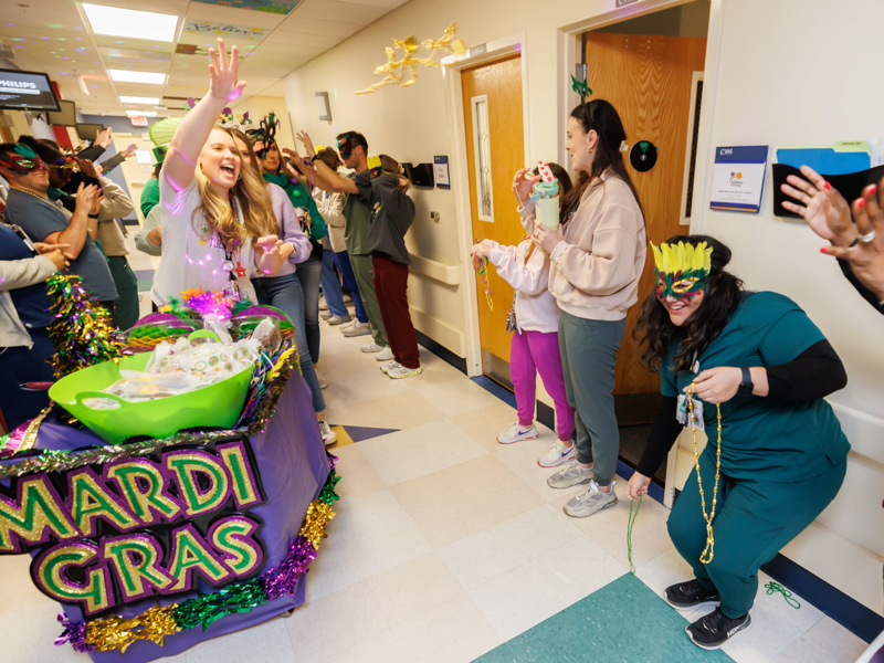 Child life specialist Madeline Wilson tosses beads during a Mardi Gras parade on Fat Tuesday. Melanie Thortis/ UMMC Photography