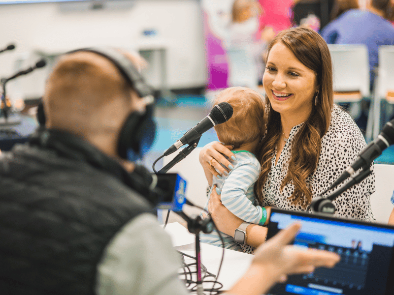 Nikki Neely holds son Charlie while doing an interview with Ryan Johnson of Q101. Lindsay McMurtray/ UMMC Communications