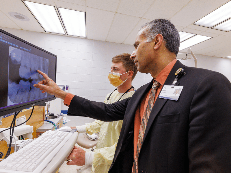 Dr. Sreenivas Koka, dean of the School of Dentistry, examines patient's X-rays with fourth-year dental student, Tripp Savage.