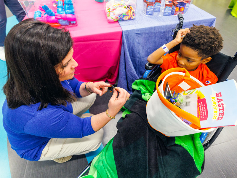 Trustmark senior vice president and director of corporate communications and marketing Melanie Morgan, a past board chair of Friends of Children's Hospital, helps Children's of Mississippi patient Zion Taylor of Jackson choose his Easter goodies.