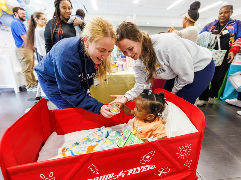 UMMC School of Nursing student Corine Thier and certified registered nurse anesthetist Alexandra Wier share an Easter surprise with Children's of Mississippi patient Z'Kyrah Ketchson of Yazoo City.