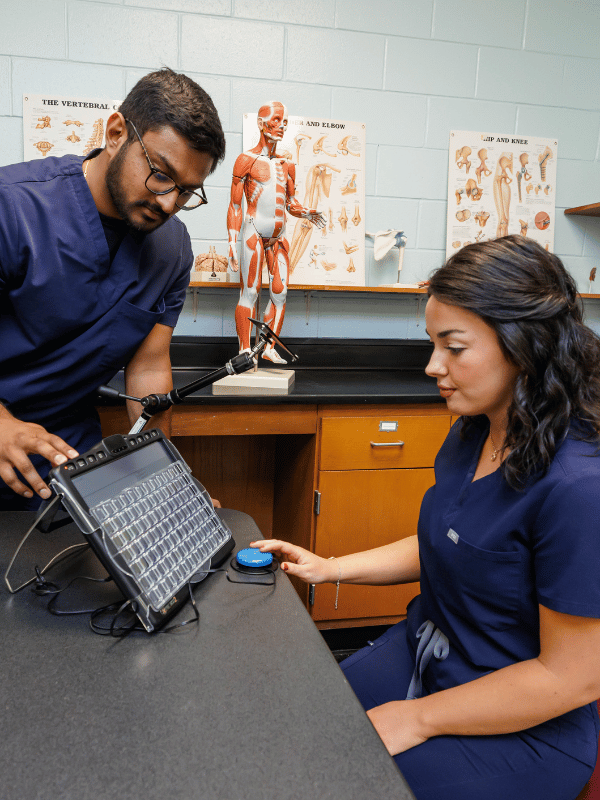 Second-year OT students Tejay Patel and Abbey Stanford simulate a communication device used in patient therapy. Melanie Thortis/ UMMC Communications 