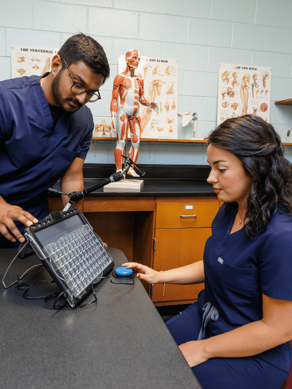 Second-year OT students Tejay Patel and Abbey Stanford simulate a communication device used in patient therapy. Melanie Thortis/ UMMC Communications