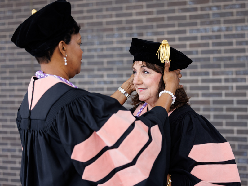 Doctor of Nursing Practice graduate Stacia Dunson, left, helps fellow graduate Betty Loflin adjust her cap before Commencement. Jay Ferchaud/ UMMC Communications 