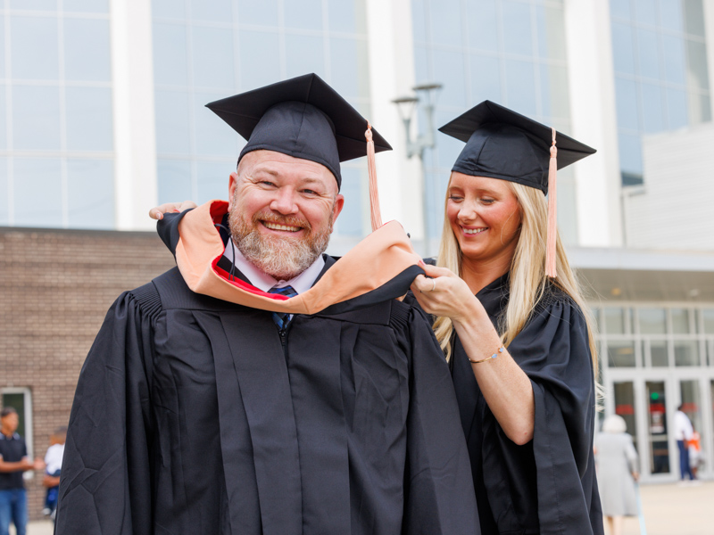 Anna Welborn, a cum laude graduate of the BSN program in the School of Nursing, helps her dad, George Doby, get ready for the University of Mississippi Medical Center's 68th annual Commencement. Dolby, a summa cum laude graduate, earned his Master of Science in Nursing. Jay Ferchaud/ UMMC Communications 