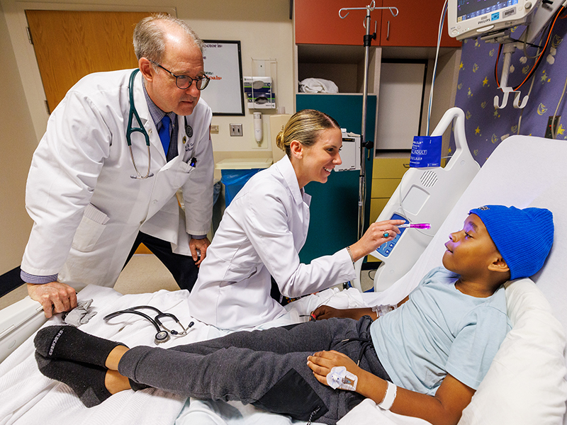 Dr. Jeff Crout, professor of pediatrics, is on hand as Estelle Blair examines patient Micah Warren, 8, of Starkville. Blair chose to stay at UMMC for her residency in pediatrics-neurology.