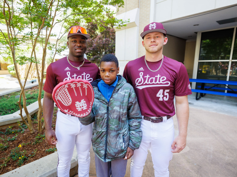 Elijah Corden, of Meridian, a patient at Children's of Mississippi, with MSU players Dakota Jordan and Tyler Davis.