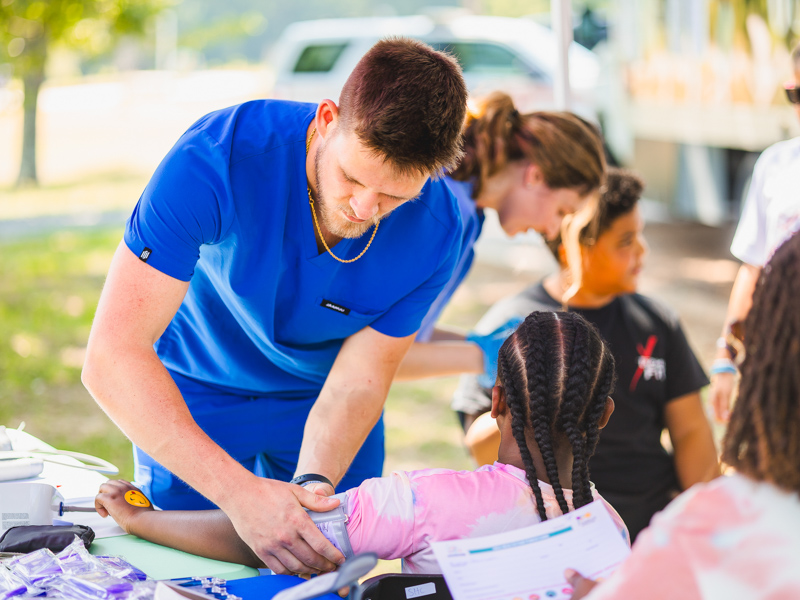 Second-year medical student Parker Jones checks Kyleigh Johnson's blood pressure as part of a Back-to-School Health Rally.