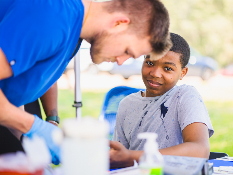 Second-year medical student Parker Jones provides a blood glucose screening to Landon Steel.