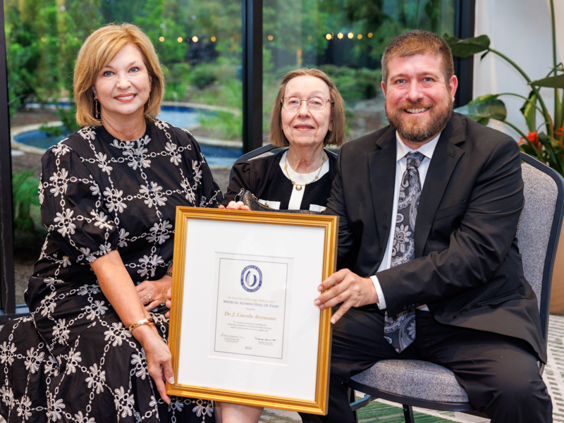 In honor of the late Dr. J. Lincoln Arceneaux, Dr. LouAnn Woodward presents the Medical Hall of Fame award to Arceneaux's wife, Dr. Jean Arceneaux, and his son, Dr. Jacques Arceneaux.