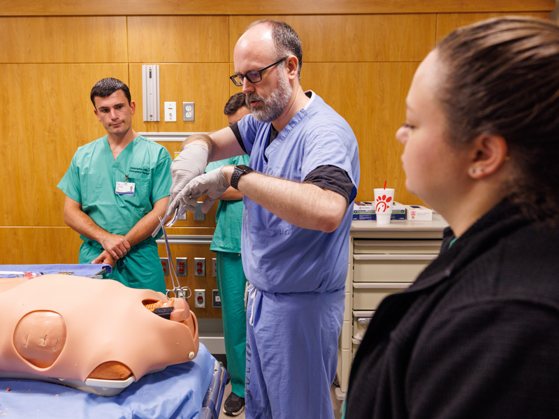 Dr. Joseph Doherty, center, assistant professor of emergency medicine, shows new residents how to insert a chest tube in a simulation exercise. Jay Ferchaud/ UMMC Communications 