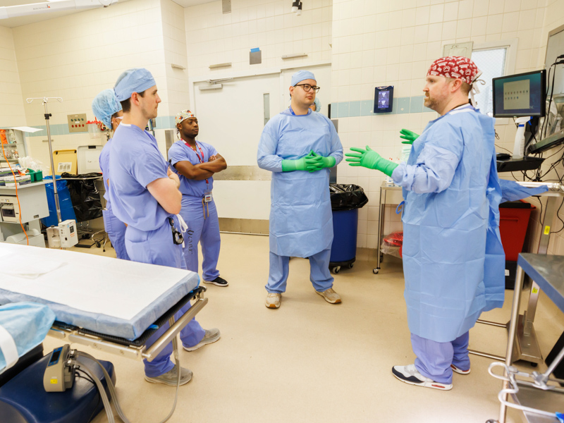 Surgical tech James Burnett, right, demonstrates proper gown procedure in the operating room with Dr. Humberto Aparicio, center, and fellow residents. Melanie Thortis/ UMMC Communications 