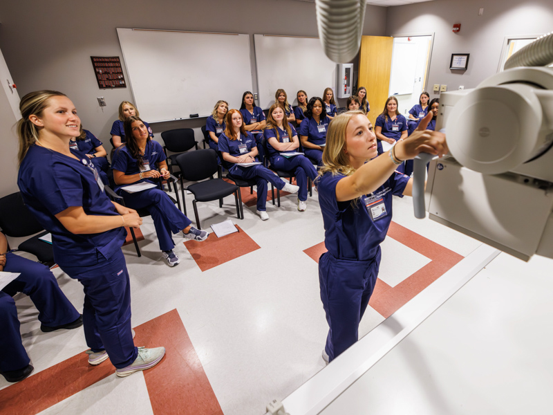 Radiologic sciences students Lauren Dungan, center, and Sidney St. Amant practice using lab equipment during the first week of classes. Melanie Thortis/ UMMC Communications