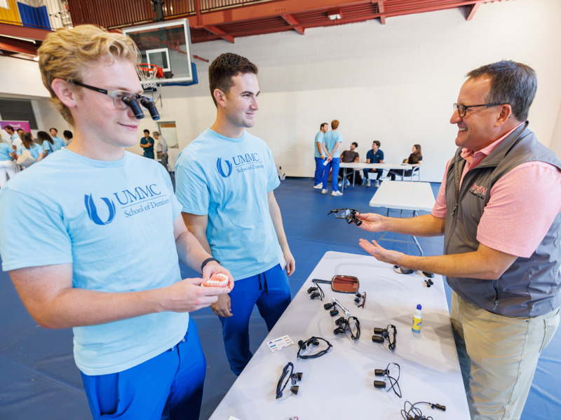 First-year dental students Christopher Cronin, left, and Caden Grover, try on surgical glasses with manufacturer representative Scott Walker during the student organization fairĀ at the Norman C. Nelson Student Union. Melanie Thortis/ UMMC Communications