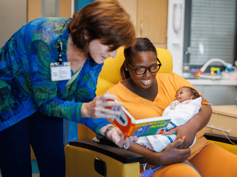 Dr. Mary Taylor, Suzan B. Thames Chair and professor of pediatrics, reads "Goodnight, Moon" to Ja'layshia Sacus, held by mother Tarnisha Garcia of Columbus. Joe Ellis/ UMMC Communications