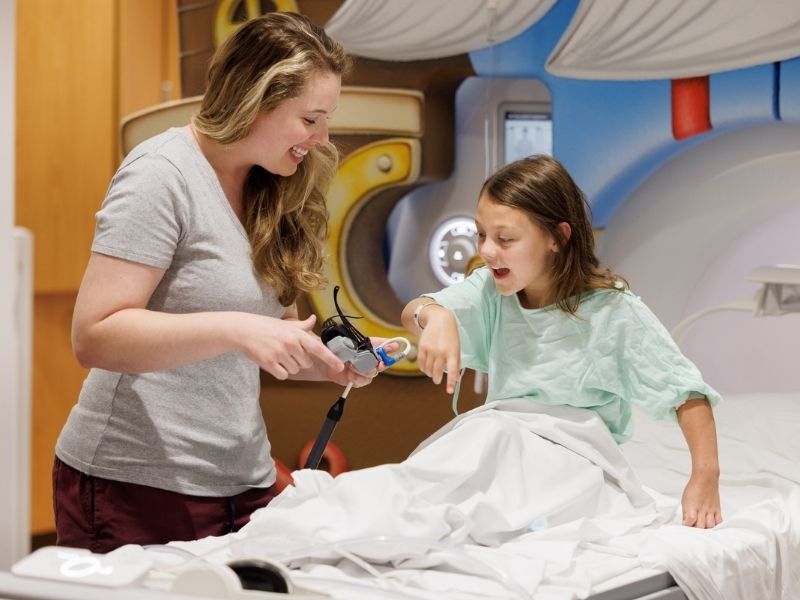 Child life specialist Madeline Wilson helped patient Everly Farris cope with getting an MRI without sedation in this file photo. Joe Ellis/ UMMC Communications