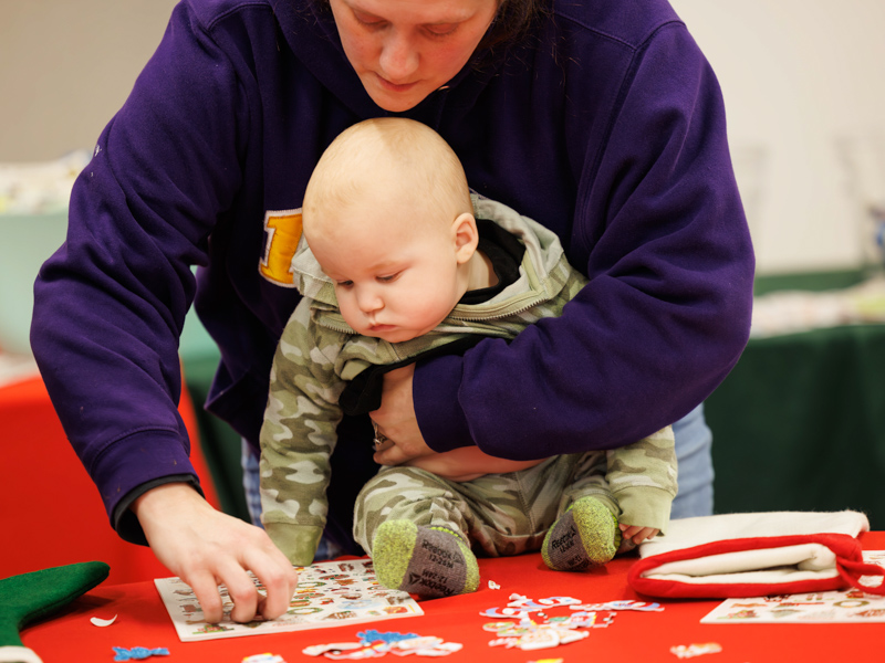 Charles Turner of Utica watches as his mother, Amanda Morris, decorates his Christmas stocking with stickers. Melanie Thortis/ UMMC Communications