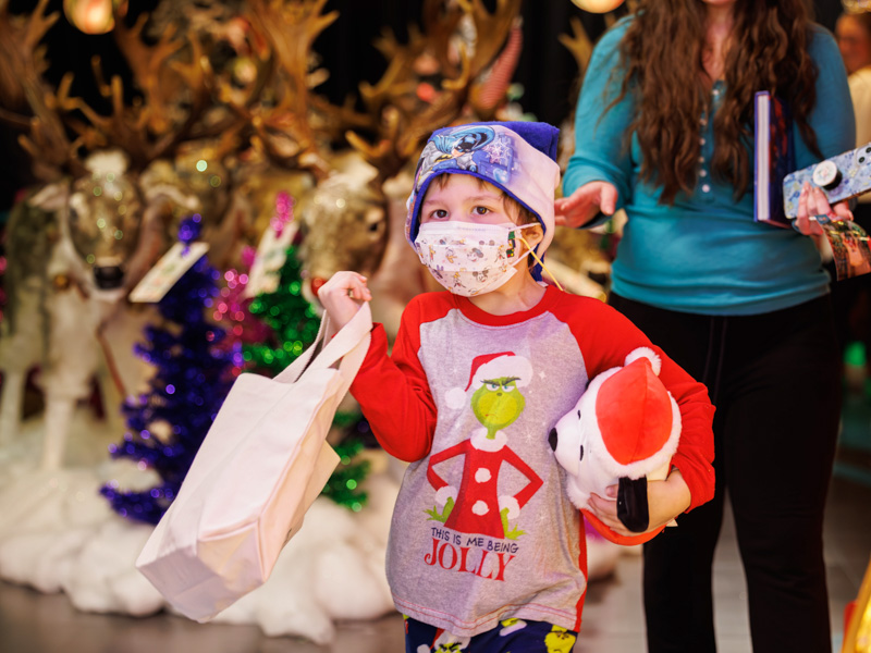 Children's of Mississippi patient Jaxon Shepherd of Columbia carries a bag filled with decorations for his Christmas tree during his visit to BankPlus Presents Winter Wonderland and Ace Tree Farm. Melanie Thortis/ UMMC Communications