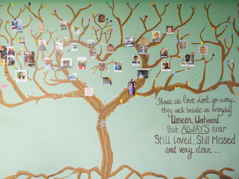A mural of a tree holds snapshots of people Stewpot has ministered to and who have recently passed away.