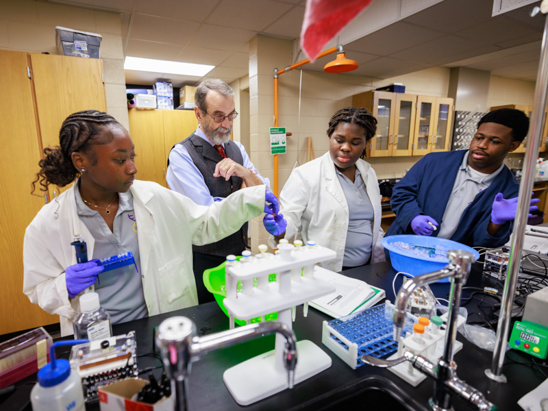 Under the watchful eye of Dr. Rob Rockhold, Hattiesburg High students (from left) Logan Hughes, Myah Eaton and Jemele Moore work as a team in their school lab.
