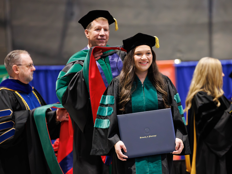 During UMMC's May 23 Commencement ceremony, Dr. Adrian Oudomrath Speyrer is hooded by Dr. Michael McMullan, professor of medicine-cardiology and associate dean of student affairs in the School of Medicine.