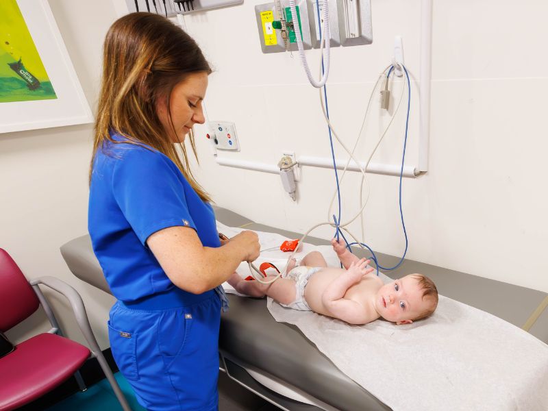 Registered nurse MacKenzie Maier checks the vital signs of patient Jameson Moak of Florence.