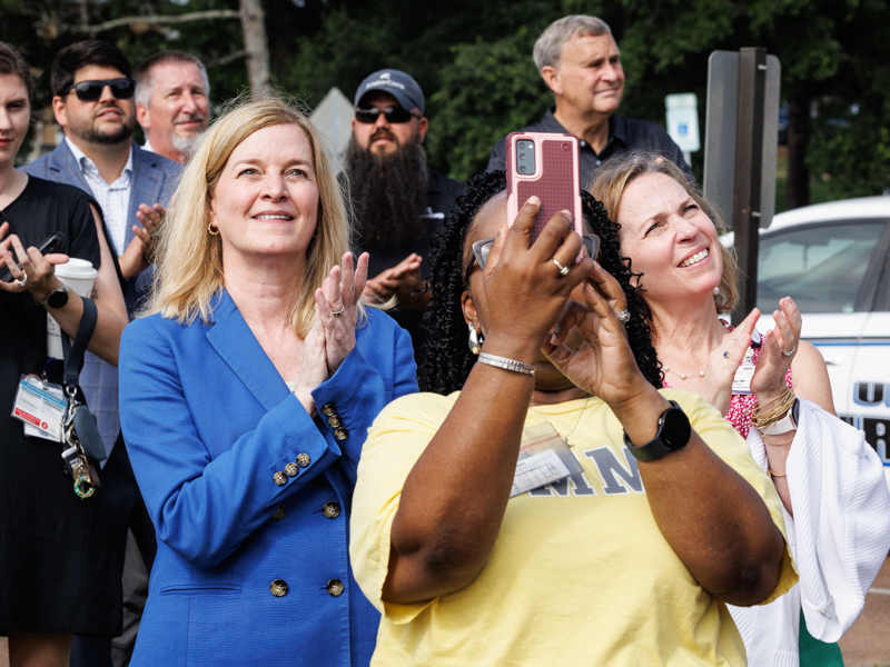 School of Nursing Dean Dr. Tina Martin, left, and Dr. Sharon McElwain, associate dean for academic affairs, react to the beam being placed on top of roof of the new building as Susie Deloach, nursing education administrator, videos the event on her phone.
