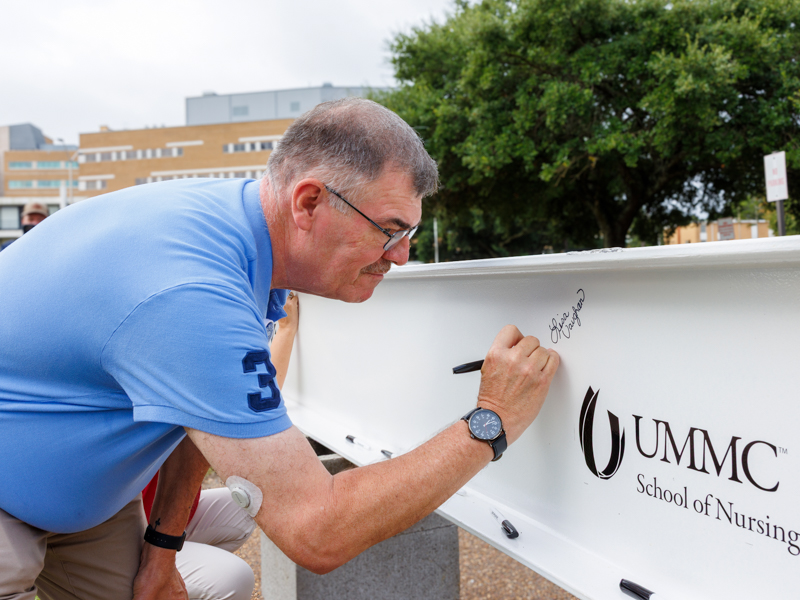 Carl Magngum, associate professor for the School of Nursing signs the beam to be placed on top of the new building. Jay Ferchaud/ UMMC Communications