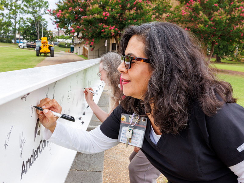 Dr. Eloise Lopez-Lambert, assistant professor, signs the beam to be placed at the top of the new UMMC School of Nursing. Jay Ferchaud/ UMMC Communications