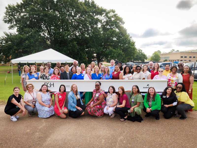 UMMC Nursing faculty smile with the beam before it was placed at the top of the new School of Nursing during a topping-out ceremony Friday. Joe Ellis/ UMMC Communications
