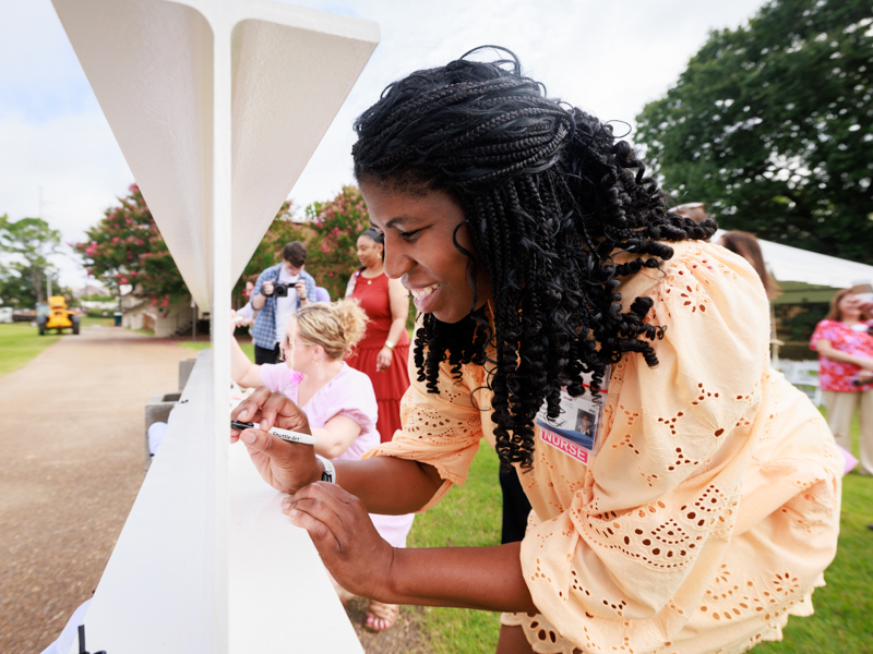 Sharron Taylor, nursing instructor, signs the beam shortly before it was placed at the top of the new UMMC School of Nursing now under construction. Joe Ellis/ UMMC Communications