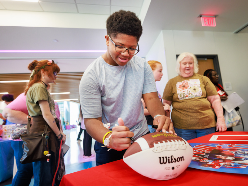 Children's of Mississippi patient Jeremiah Newell of Brandon signs an Ole Miss football. Joe Ellis/ UMMC Communications