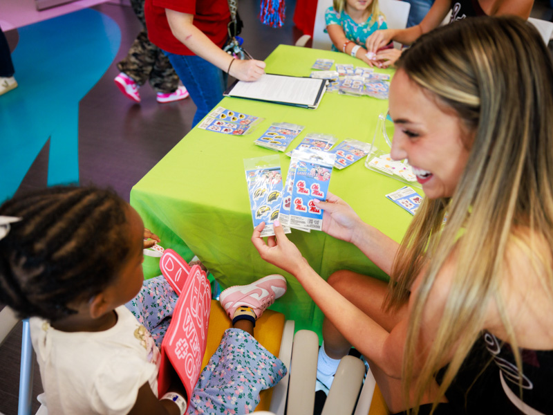 Children's of Mississippi patient Khalea McGee of Yazoo City gets college stickers from Mississippi State University cheerleader Kaileigh Manosar. Joe Ellis/ UMMC Communications