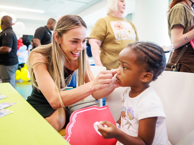 Mississippi State University cheerleader Kaileigh Manosar places a sticker on the cheek of Children's of Mississippi patient Khalea McGee of Yazoo City.