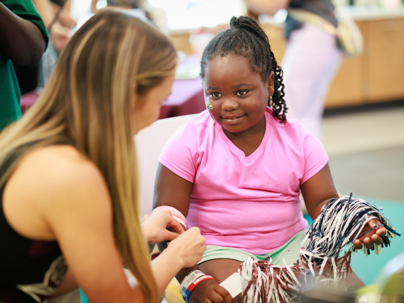 Children's of Mississippi patient Zy'ion Meardry of Waynesboro visits with a cheerleader from Mississippi State University. Joe Ellis/ UMMC Communications