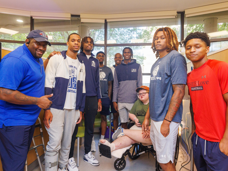 Children's of Mississippi patient Blake Stone smiles in a photo with Jackson State University basketball players. Jay Ferchaud/ UMMC Communications