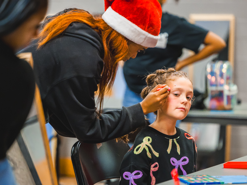 Gates Hogg, daughter of UMMC School of Nursing instructor Hannah Hogg and a Children's of Mississippi patient, gets a makeup application from Smith County Career Center student Tamecia.
