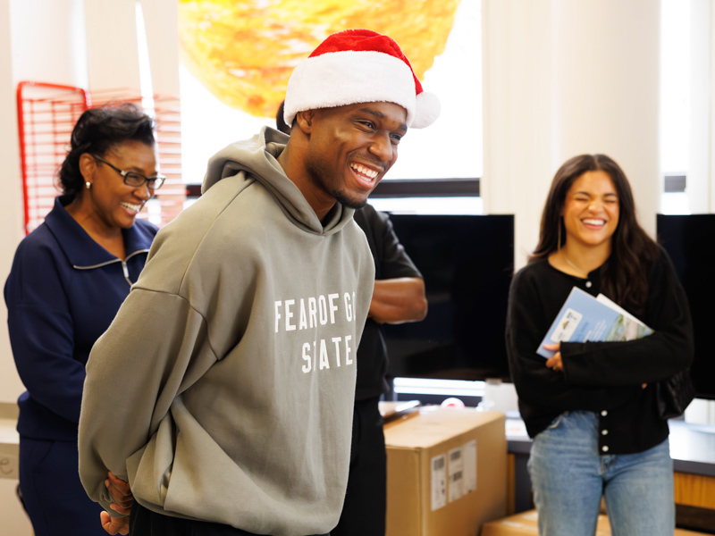 MSU basketball player Josh Hubbard brings festive cheer to Children's of Mississippi with presents. Melanie Thortis/ UMMC Communications 