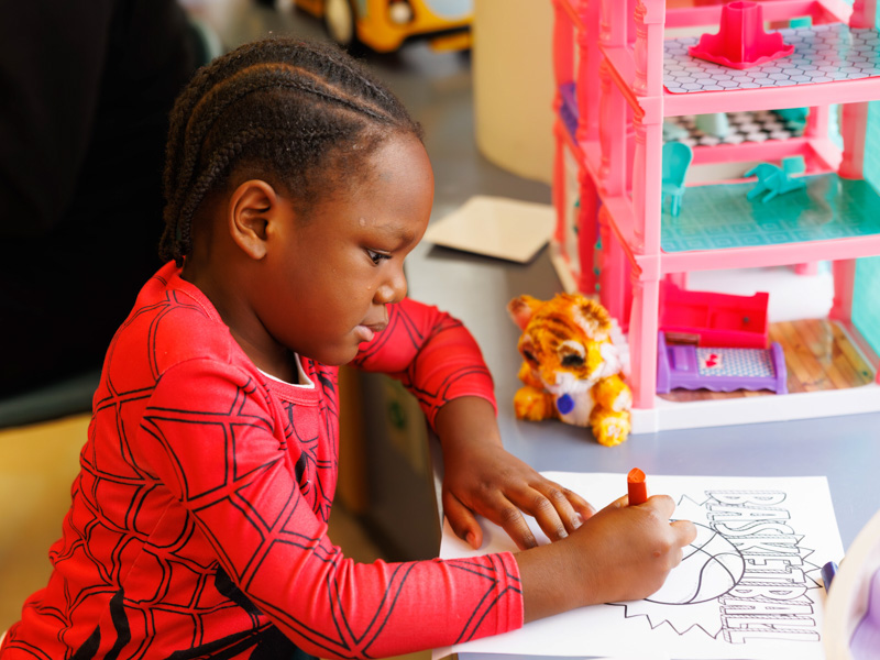 Cortay Jenkins, 5, of Hattiesburg, colors in a basketball with MSU basketball player Josh Hubbard. Melanie Thortis/ UMMC Communications