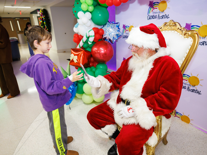 Payton Culpepper, 8, lets Santa borrow his phone so his sister, Alanna Howard, can call in her Christmas wish list. Melanie Thortis/ UMMC Communications