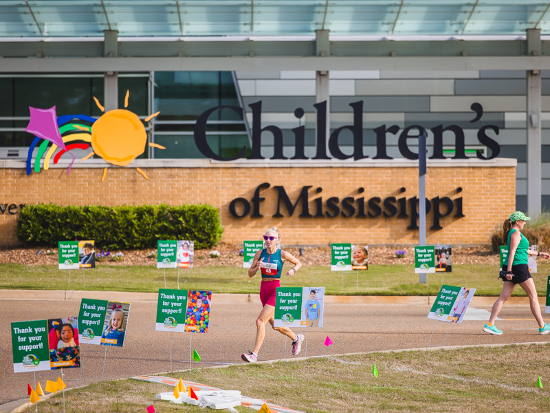 A half marathon runner in the 2026 Run the Rainbow race benefitting Children's of Mississippi races in front of the children's hospital.