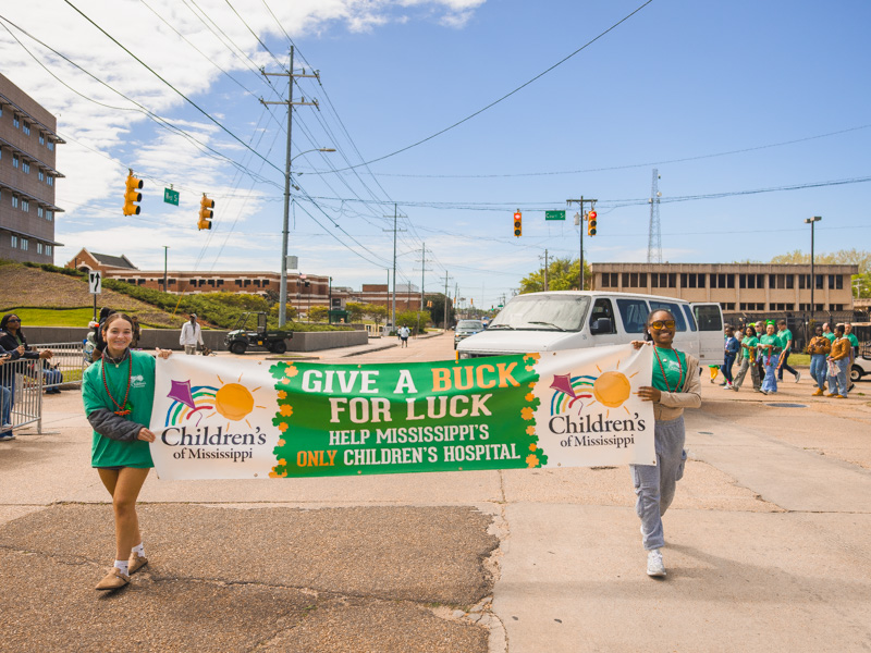 Briley Carson and Morgan Hightower, development specialist at UMMC, lead the way with a banner promoting City Sweep benefitting the state's only children's hospital. Lindsay McMurtray/ UMMC Communications
