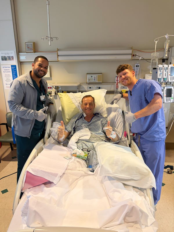 SICU nurses, Isaac Glenn, left, and Daygon Williams, pose for a photo with liver transplant patient Wade Watts.