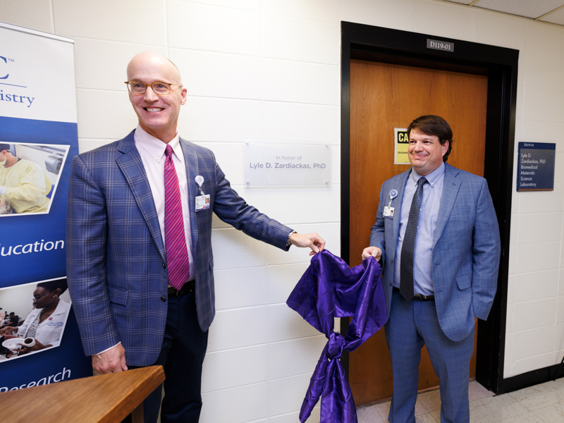 Dr. Scott Rodgers, associate vice chancellor, left, and Dr. Lee Bidwell, associate vice chancellor for research, unveil signage for the Lyle D. Zardiackas, PhD Biomedical Materials Science Laboratory.